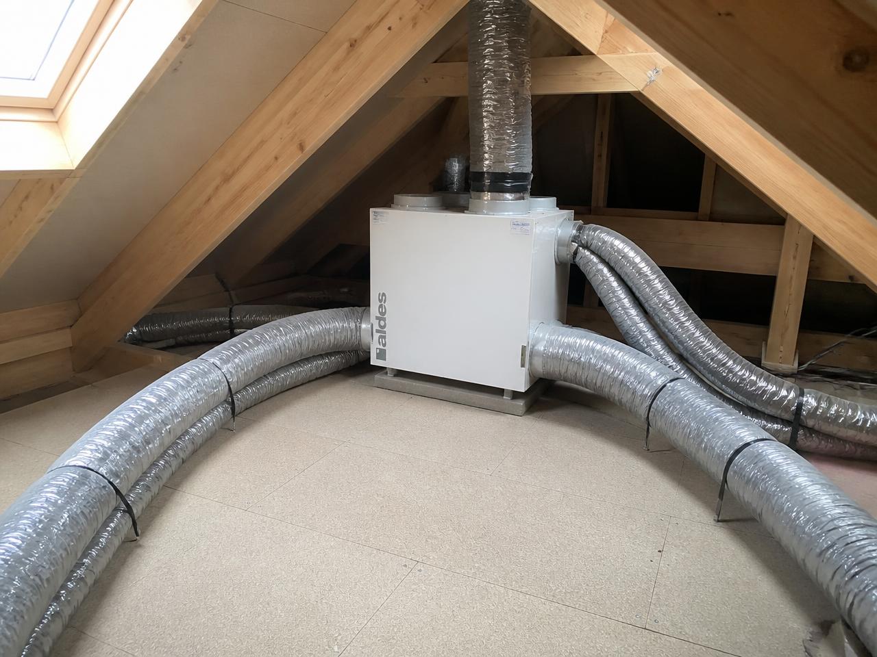 Caisson de VMC installé dans les combles d'une maison, avec gaines isolées raccordées